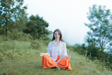 Seseorang sedang melakukan meditasi tenang di alam terbuka untuk menerapkan cara mengurangi stres