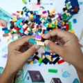 Anak laki-laki sedang menyusun balok kayu warna-warni sebagai permainan edukatif anak
