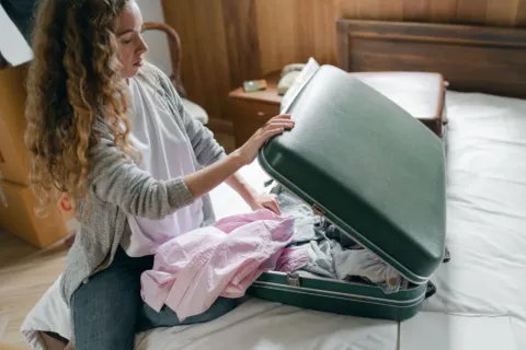 Persiapan sebelum traveling dengan menata pakaian dan dokumen di dalam koper