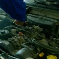 Mekanik sedang menuangkan oli kendaraan baru ke dalam mesin mobil untuk perawatan rutin.