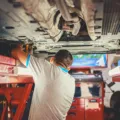 Mekanik sedang melakukan inspeksi mesin dalam tips merawat mobil bekas agar tetap prima