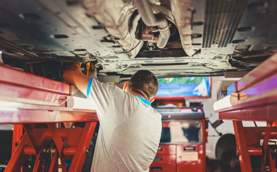 Mekanik sedang melakukan inspeksi mesin dalam tips merawat mobil bekas agar tetap prima
