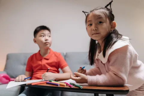 Aktivitas anak di rumah sedang bermain membuat kerajinan tangan bersama saudara