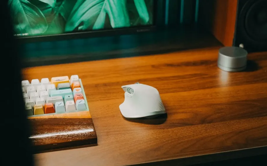 Pengguna sedang menggenggam mouse ergonomis nirkabel di atas meja kerja yang rapi