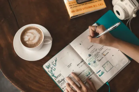 Seseorang sedang merapikan buku agenda untuk mengatur rutinitas harian yang produktif