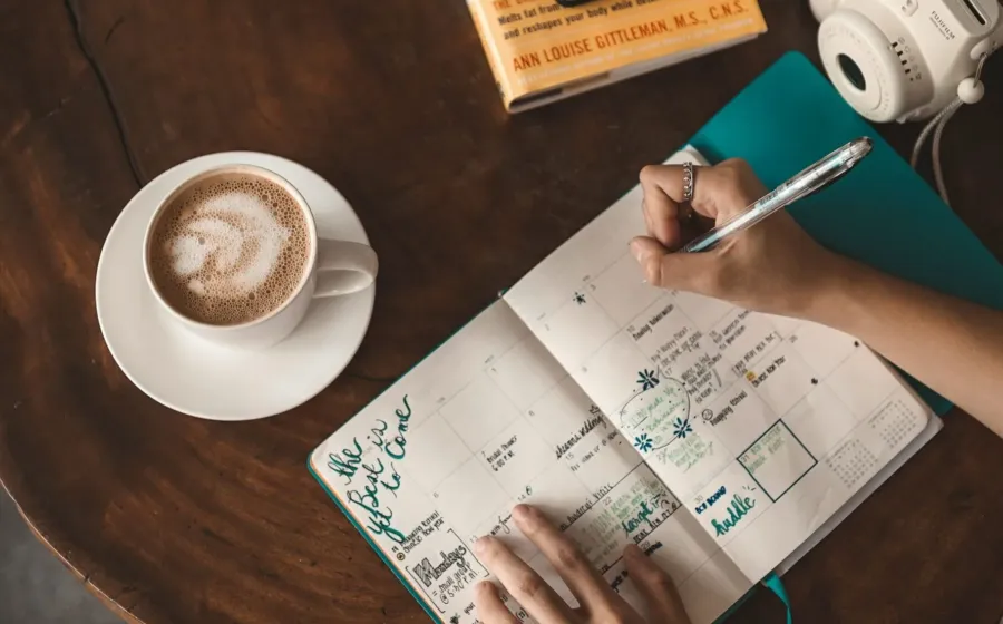 Seseorang sedang merapikan buku agenda untuk mengatur rutinitas harian yang produktif