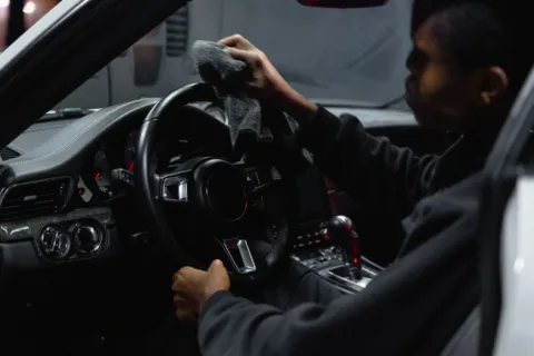 Proses membersihkan interior mobil menggunakan lap mikrofiber pada bagian dasbor agar bebas debu