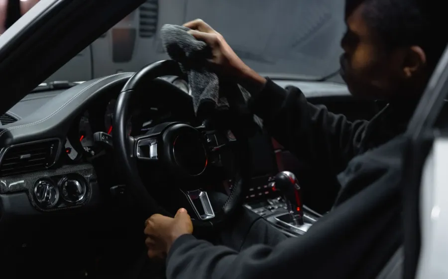 Proses membersihkan interior mobil menggunakan lap mikrofiber pada bagian dasbor agar bebas debu