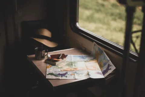 Ilustrasi tips membuat itinerary perjalanan dengan peta wisata dan catatan rencana liburan