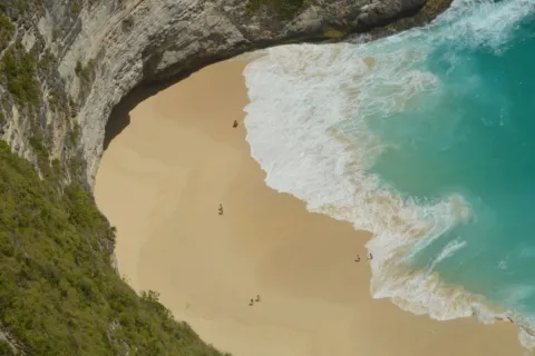 Pemandangan pasir putih dan air laut biru jernih di salah satu destinasi wisata pantai terbaik Indonesia