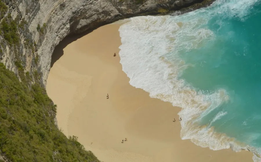 Pemandangan pasir putih dan air laut biru jernih di salah satu destinasi wisata pantai terbaik Indonesia