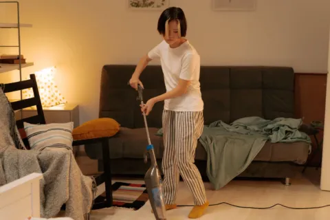 Seseorang sedang menerapkan cara membersihkan rumah menggunakan kain lap mikrofiber pada permukaan meja kayu
