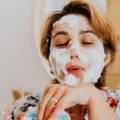 Ilustrasi cara membersihkan wajah dengan mengusapkan air hangat secara lembut di kamar mandi