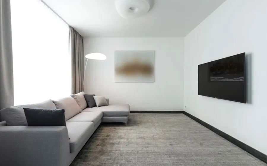 Ruang tamu mungil yang rapi dan terang dengan cermin dinding serta sofa berkaki ramping agar rumah terlihat luas