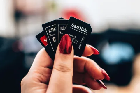 Tangan memegang kartu memori microSD dan SD card untuk kamera serta ponsel