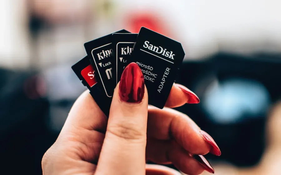 Tangan memegang kartu memori microSD dan SD card untuk kamera serta ponsel