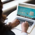 Seseorang sedang mengetik di keyboard laptop untuk kerja di meja kantor yang rapi