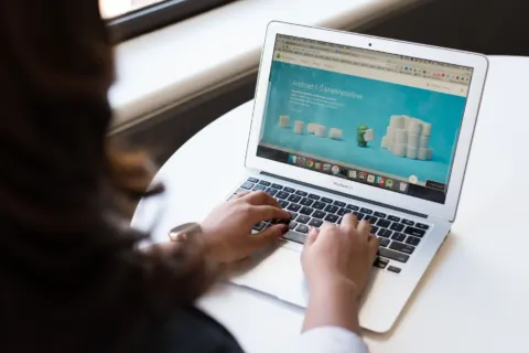 Seseorang sedang mengetik di keyboard laptop untuk kerja di meja kantor yang rapi