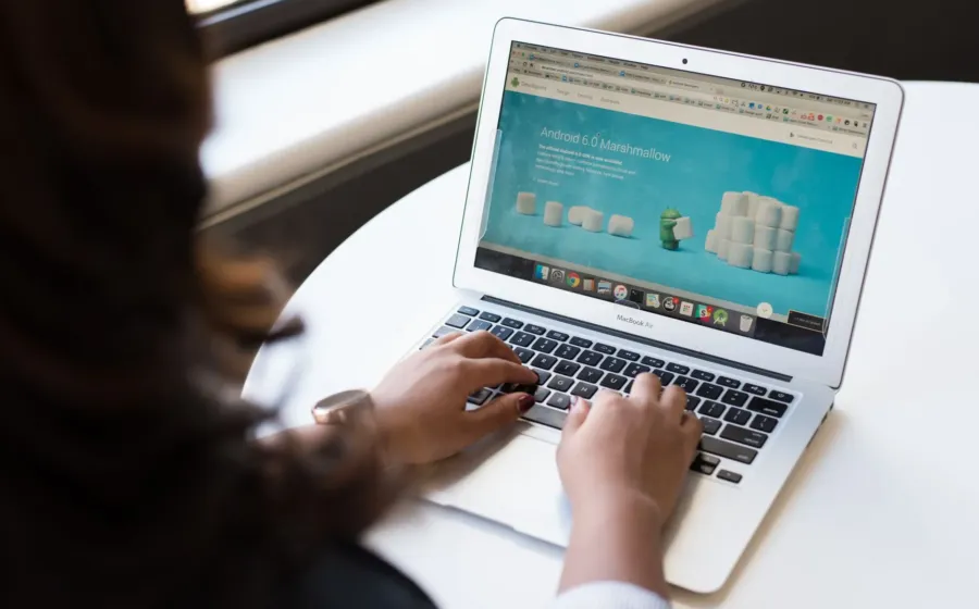 Seseorang sedang mengetik di keyboard laptop untuk kerja di meja kantor yang rapi
