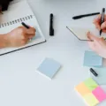 Seseorang menulis catatan untuk mempelajari cara mencari ide bisnis di buku agenda