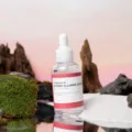 Wanita mengaplikasikan serum wajah untuk cara mengatasi bekas jerawat hitam secara rutin di pagi hari