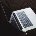 Seseorang sedang mengisi daya baterai laptop di atas meja kerja yang rapi