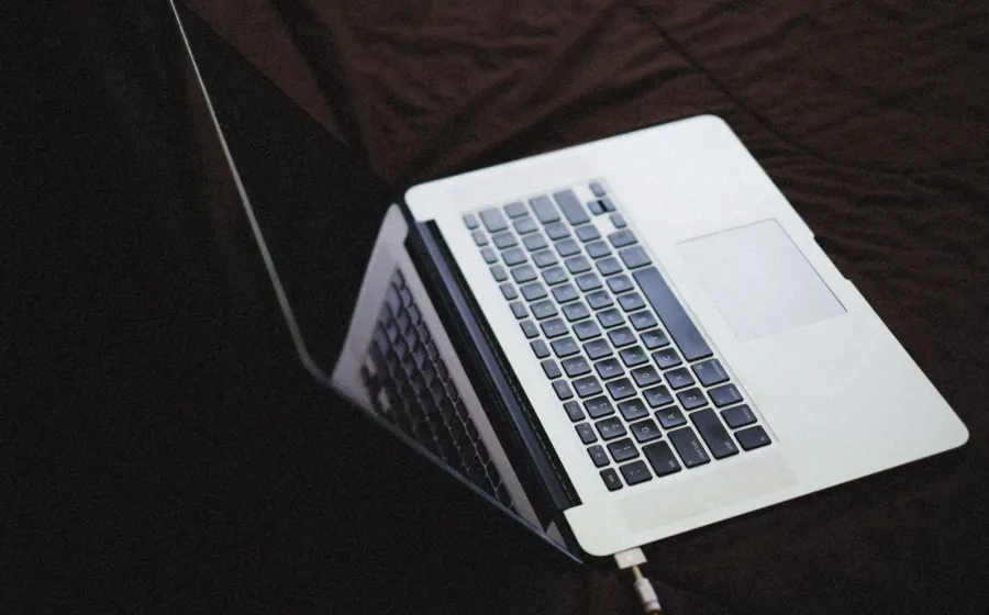 Seseorang sedang mengisi daya baterai laptop di atas meja kerja yang rapi