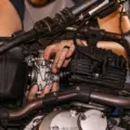 Mekanik sedang merawat mesin motor dan mengecek oli di bengkel