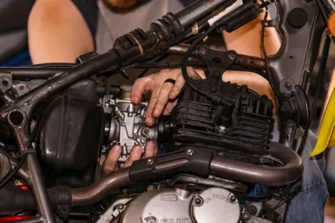 Mekanik sedang merawat mesin motor dan mengecek oli di bengkel