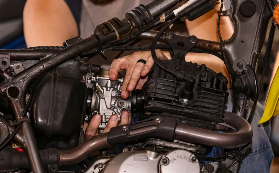 Mekanik sedang merawat mesin motor dan mengecek oli di bengkel