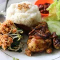 Makanan untuk kesehatan tubuh berupa piring berisi sayuran hijau, tempe, dan buah segar