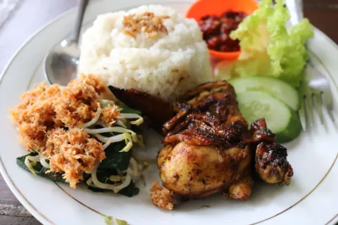 Makanan untuk kesehatan tubuh berupa piring berisi sayuran hijau, tempe, dan buah segar