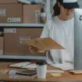 Seseorang sedang menyiapkan paket produk untuk pesanan toko online di atas meja kerja
