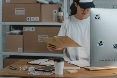 Seseorang sedang menyiapkan paket produk untuk pesanan toko online di atas meja kerja