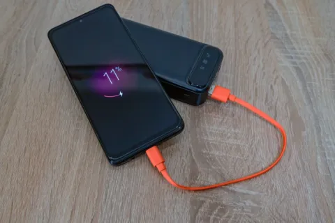 Tips memilih power bank yang aman sedang mengisi daya baterai ponsel pintar di meja