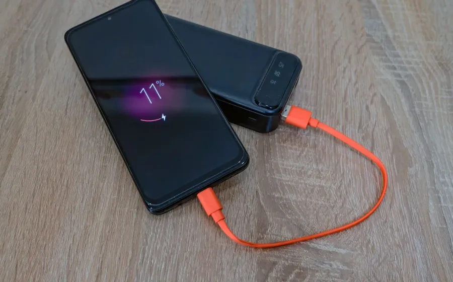 Tips memilih power bank yang aman sedang mengisi daya baterai ponsel pintar di meja