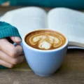 Seseorang sedang bersantai menerapkan tips mengelola waktu luang dengan membaca buku di dekat jendela