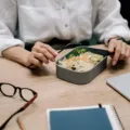 Pekerja kantor merapikan posisi laptop di meja kerja untuk menjaga kesehatan di tempat kerja
