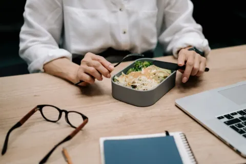 Pekerja kantor merapikan posisi laptop di meja kerja untuk menjaga kesehatan di tempat kerja
