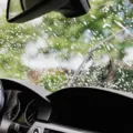 Seseorang membilas mobil dengan air bersih sebagai bagian dari tips merawat mobil saat hujan.