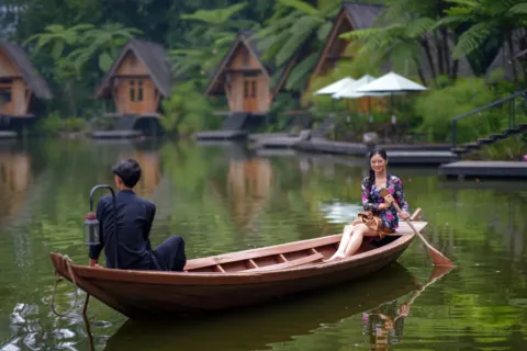 Pasangan berjalan santai di kebun teh kawasan wisata romantis untuk pasangan di Bandung